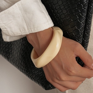 Détail d'un bracelet manchette géométrique en résine crème sur le poignet d'un mannequin