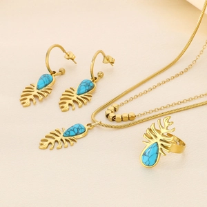 Détail d'une parure de bijoux feuille avec turquoise bleue sur chaîne serpent dorée