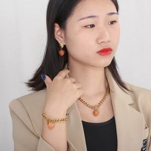 Detail of gold OT clasp jewelry set featuring heart-shaped orange-red gemstones