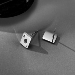 Macro shot of silver poker Ace of Clubs and rectangular stud earrings in black and white