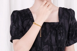 Detailed view of adjustable gold beaded bracelet with lobster clasp on model wrist