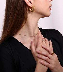 Close-up of 18K gold plated thin woven chain necklace with green zircon pendant on model