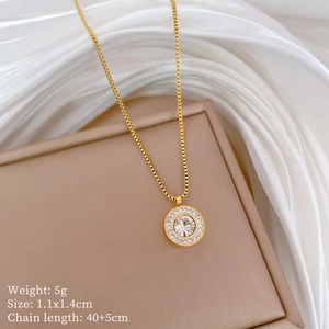 Macro shot of gold-plated circular pendant with embedded crystals and product measurements