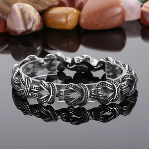 Détail macro du bracelet en acier titane style punk rétro avec motifs de nœuds et fini vieilli