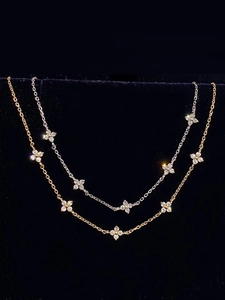 Detail of gold and silver four-leaf clover bracelets with sparkling zircon on black background