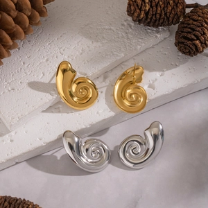 Detail of spiral conch stud earrings in gold and silver finish with macro texture