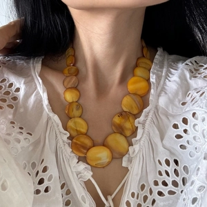 Detail of bohemian yellow beaded shell necklace featuring gradient resin disc charms