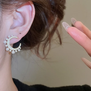 Nahaufnahme eleganter Halbmond-Ohrringe mit Mikro-Diamanten und weißen Perlen