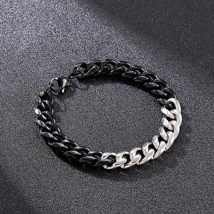 Macro view of a heavy black and silver Cuban link bracelet on a textured surface