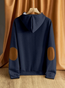 Dettaglio felpa con cappuccio blu navy con trama a nido d'ape e toppe marroni sui gomiti