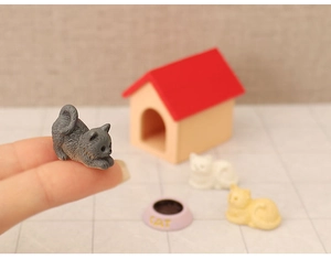 Close-up of a miniature grey resin cat figurine held in hand for a dollhouse scene