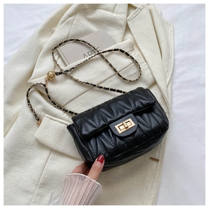 Close-up of black quilted leather texture and gold chain on stylish shoulder bag