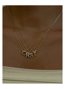 Dettaglio di una collana dorata a quattro strati con ciondoli a lettere con strass