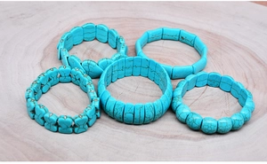 Detail view of five turquoise beaded bracelets with black marble texture on wood