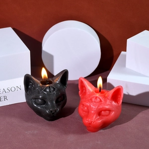 Detailed close-up of Gothic three-eyed cat candles in black and red with flame