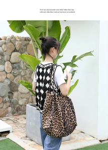 Close-up of a large leopard print tote bag paired with a casual knit vest and blue jeans