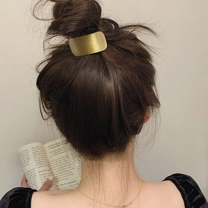 Detailed view of a matte gold rectangular metal hair tie on a bun for women