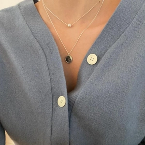 Close-up of layered 925 silver necklace with white pearl and black round pendant