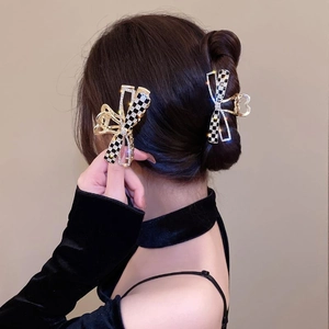 Détail d'une pince à cheveux papillon à damier avec strass sur cheveux bruns