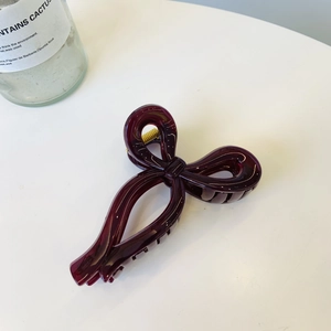 Macro shot of dark red ribbon bow hair claw clip with golden spring mechanism