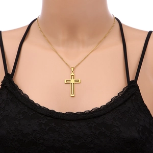 Detailed close-up of a hollow golden cross pendant necklace worn by a fashion model