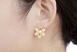 Close-up of elegant gold petal earrings with a white pearl on a female model