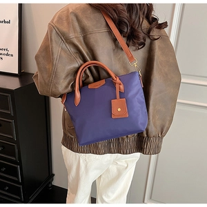Detail showing a model wearing a purple nylon tote bag with brown leather handles and strap