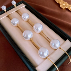 Macro view of long tassel gold chain earrings with gradient white pearls in a jewelry box