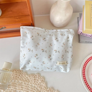 Close-up of floral fabric cosmetic bag with small flower patterns and brand label