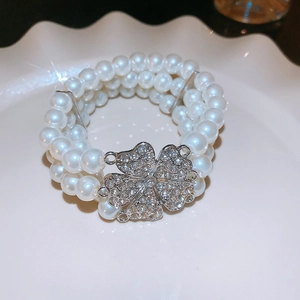 Detailed macro view of multilayered pearl bracelet with shimmering rhinestone clover clasp