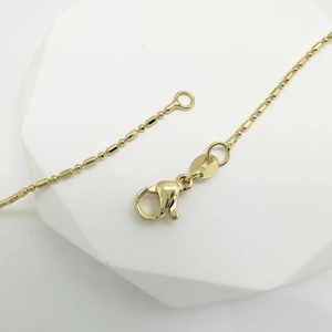 Delicate 18k gold plated teardrop necklace with lobster clasp on geometric stand
