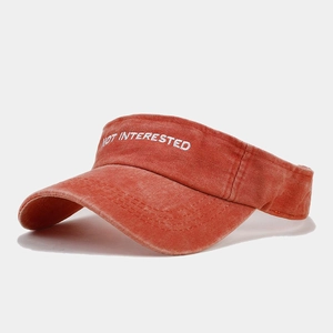 Detail of embroidered 'NOT INTERESTED' text on washed cotton burnt orange sun visor hat