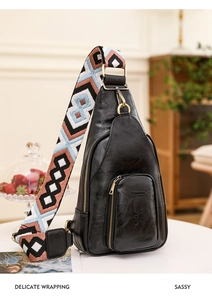 Nahaufnahme der schwarzen Leder-Brusttasche mit buntem Webgurt und goldenen Reißverschlüssen