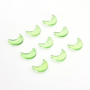 Close-up of translucent green crescent moon glass charms with glitter and hanging holes