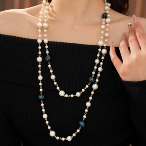 Elegant long double-layer necklace with pearls and gold chain on a female model