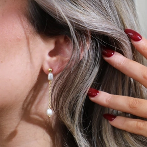 Detail of luxury S925 silver long pearl tassel drop earrings on model with golden chain
