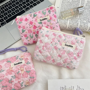 Detailed view of floral quilted cotton pouches with purple zippers and soft texture