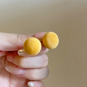 Close-up of yellow flocked round stud earrings with soft velvet texture for women