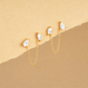 Detail of gold double piercing earring with sparkling rhinestones and delicate chains