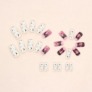 Detail view of pink gradient press-on nails with artistic black lettering and black ink spots