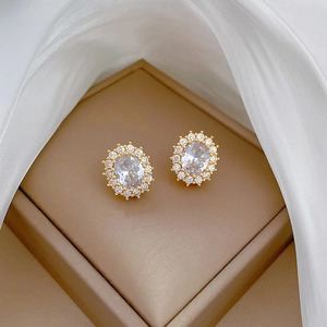 Detail of luxury oval gold halo earrings with sparkling cubic zirconia on brown display