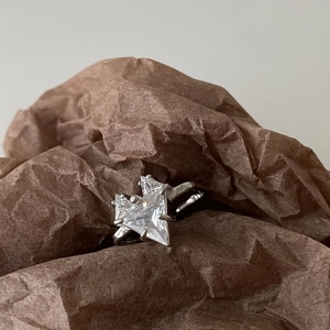 Minimalist 925 sterling silver ring with a large star-shaped clear zircon on brown paper