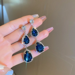 Dettaglio macro di orecchini a goccia con zaffiro blu e montatura in argento