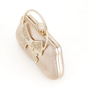 Detail of elegant gold evening clutch with sparkling rhinestones on bow and metal handle