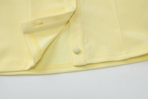 Detailed view of pale yellow fabric with fabric-covered buttons and fine stitching