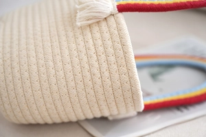 Close-up of handwoven cotton rope bag featuring a rainbow striped handle and white tassel