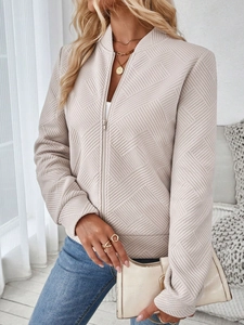 Detail shot of apricot textured jacket fabric with geometric embossed pattern and zipper