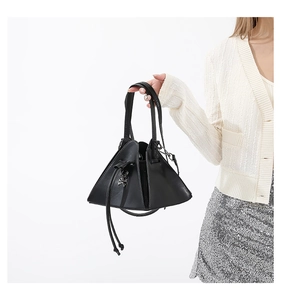 Detail of punk style triangle crossbody bag with skull ornament on a model's hand