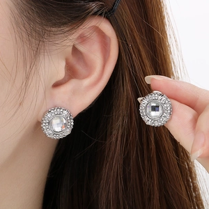 Macro shot of silver round halo stud earrings featuring a central crystal and pave stones