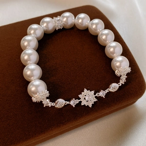 Détail d'un bracelet en perles élégant avec pendentif flocon en zircon sur écrin brun